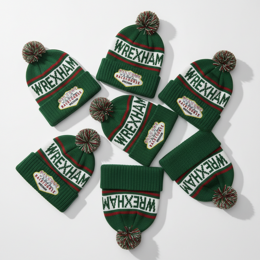 Green knit hats with 'Wrexham' text and pom-poms on a white background